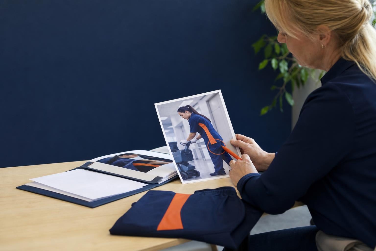 Office manager compares a cleaning job photo with an approved uniform sample beside a proposal folder